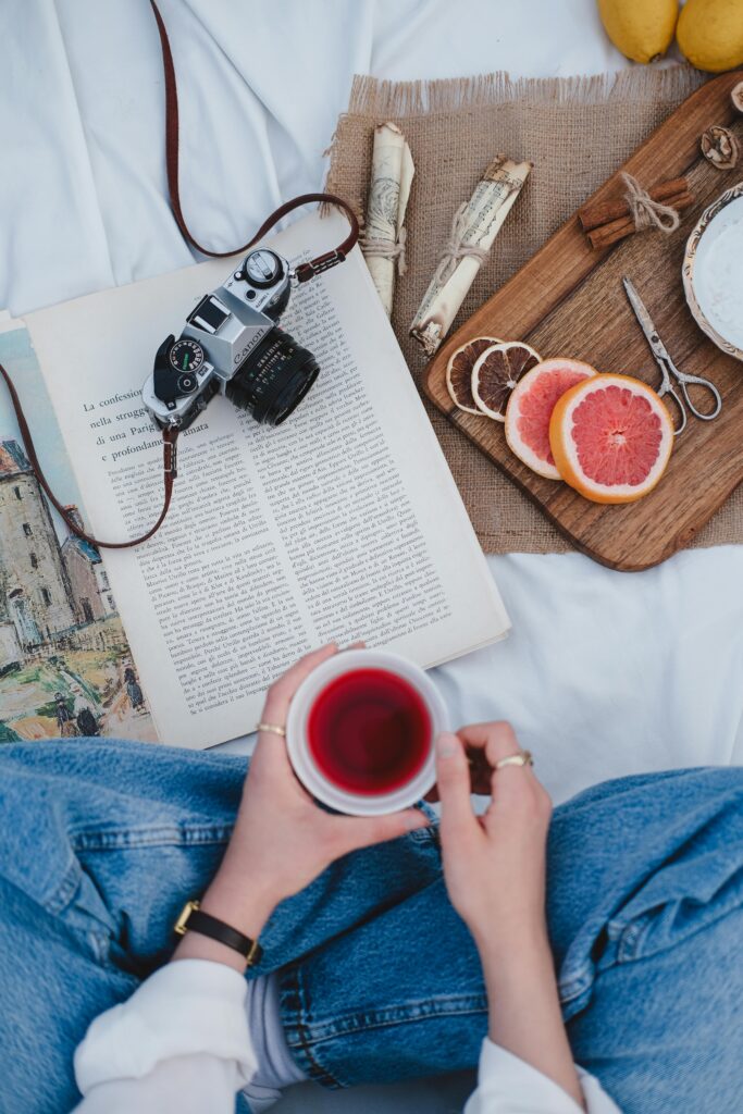 Relaxing outdoor picnic setup with a book, camera, and refreshing drink for a perfect leisure time.