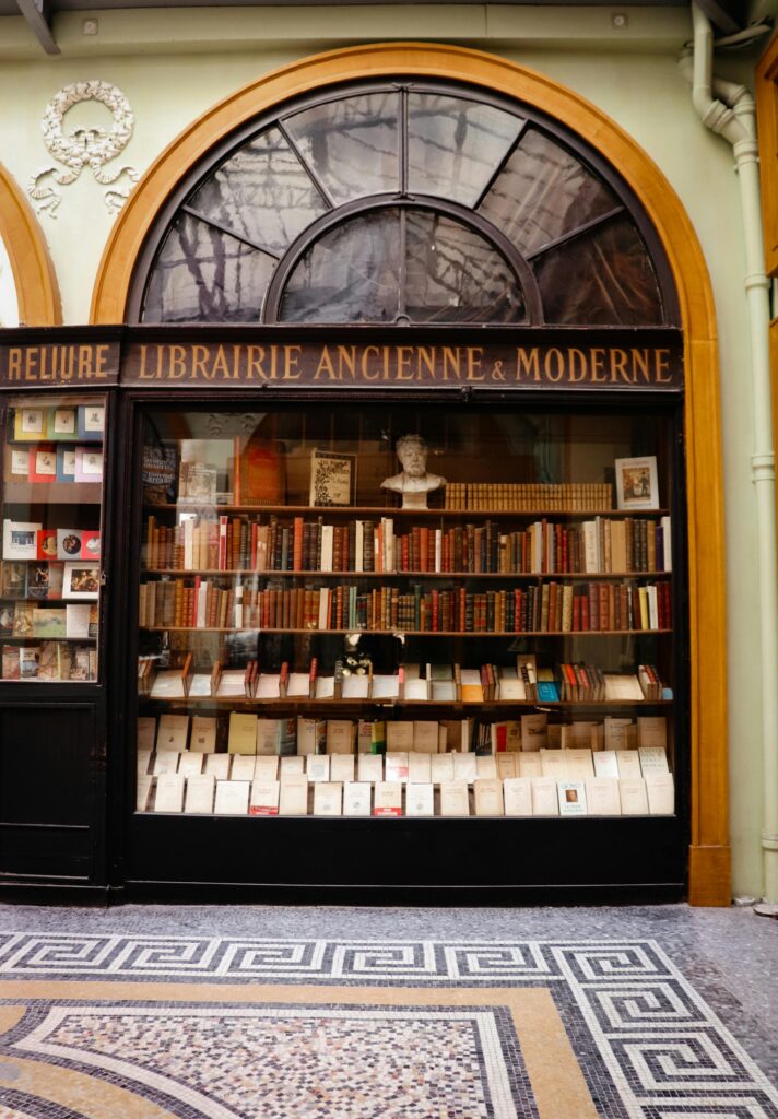 Charming exterior of a vintage bookshop with classic books and arched window display.