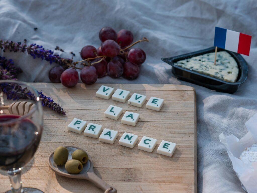 A French-themed still life with wine, cheese, grapes, and flag, celebrating French culture.