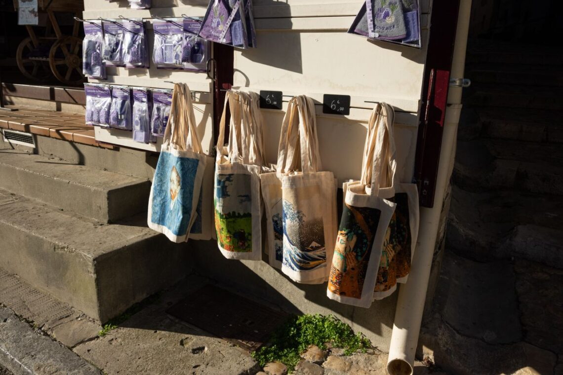 A vibrant display of canvas tote bags and lavender products in Arles, France.