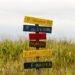 Vibrant multilingual sign in a grassy field in Guaratuba, Paraná, Brazil, showcasing local charm.
